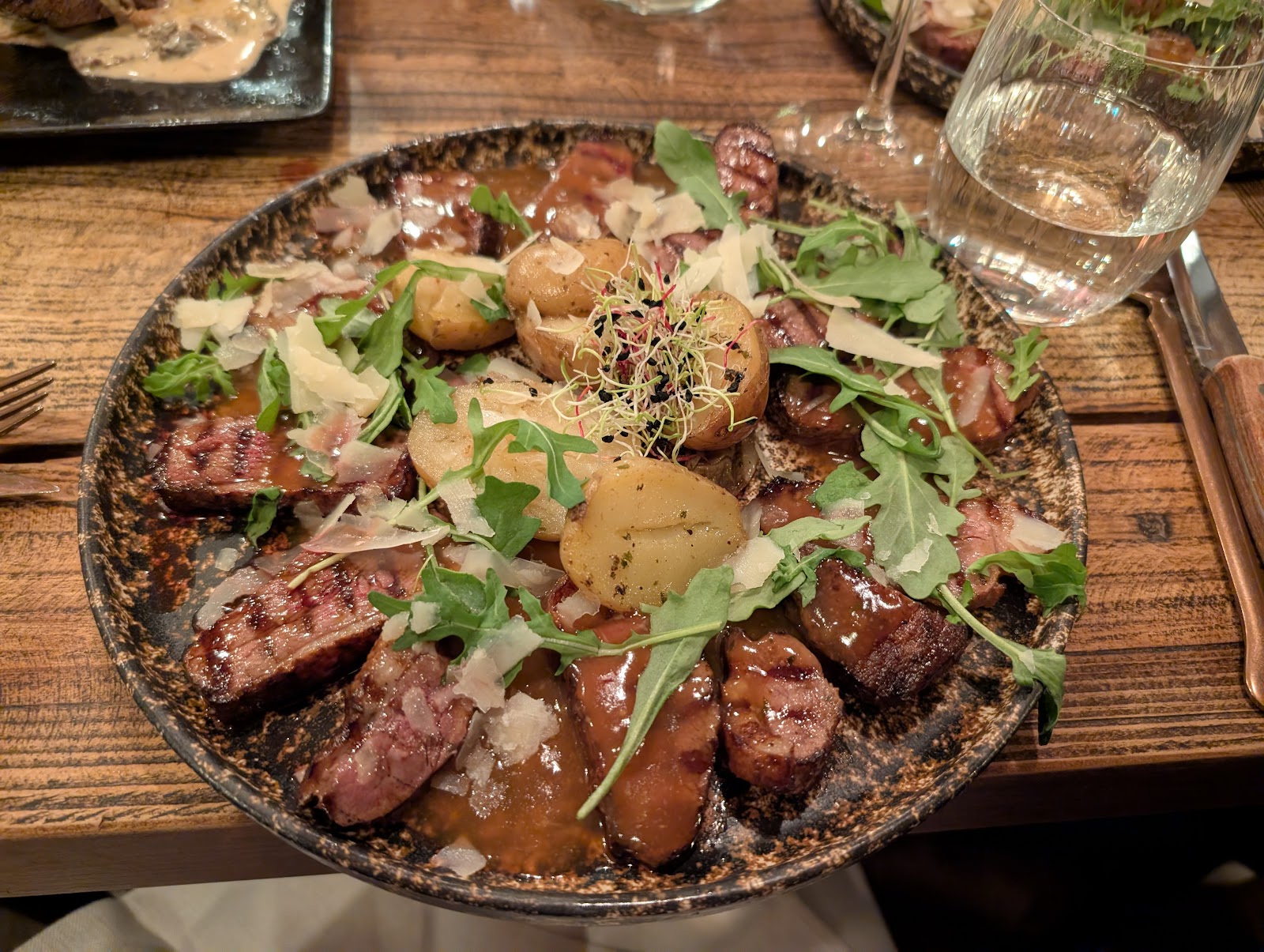 Assiette de viande grillée tranchée avec pommes de terre, roquette et parmesan
