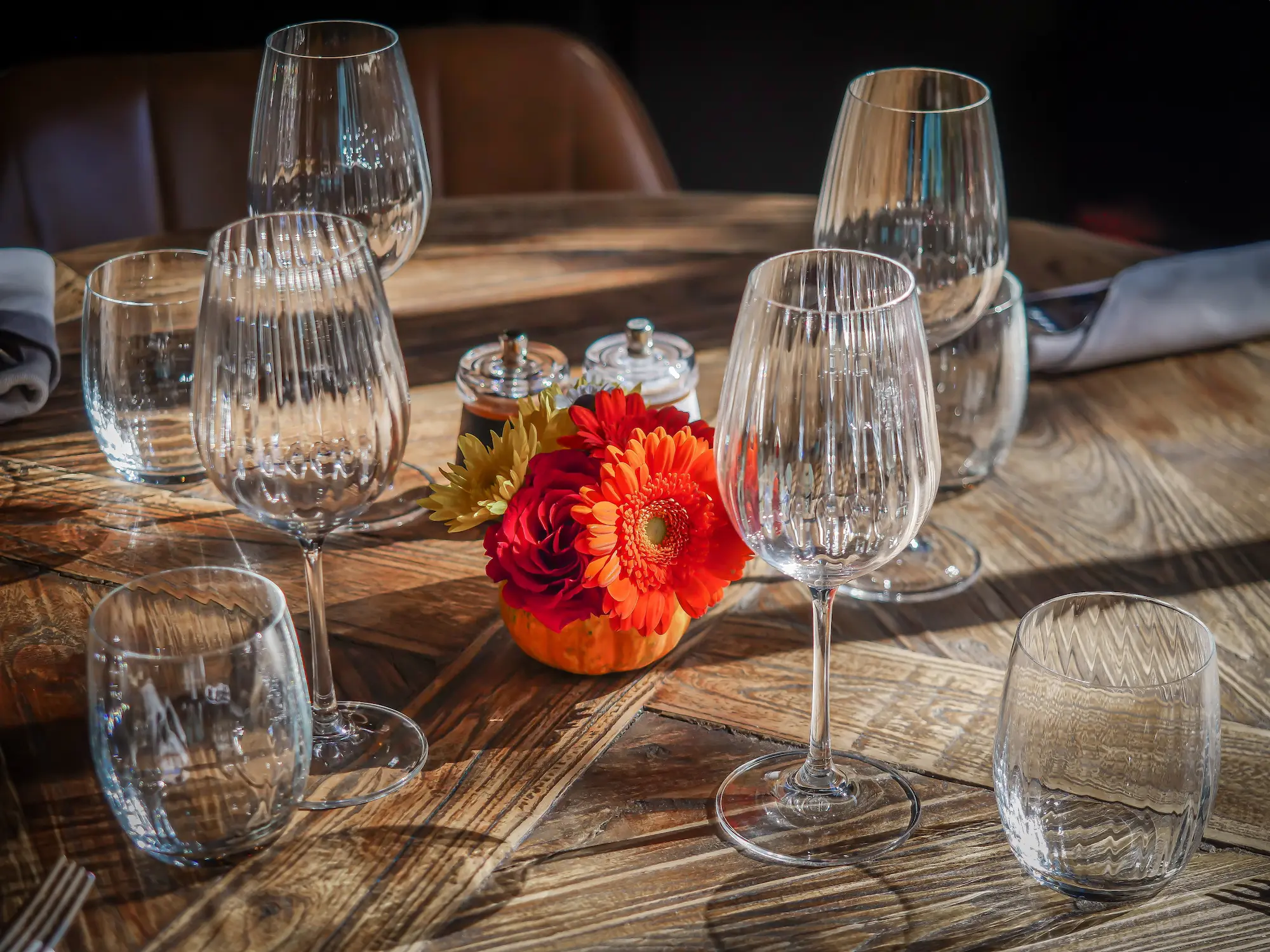 Table dressée avec verres à vin en cristal et bouquet automnal sur bois